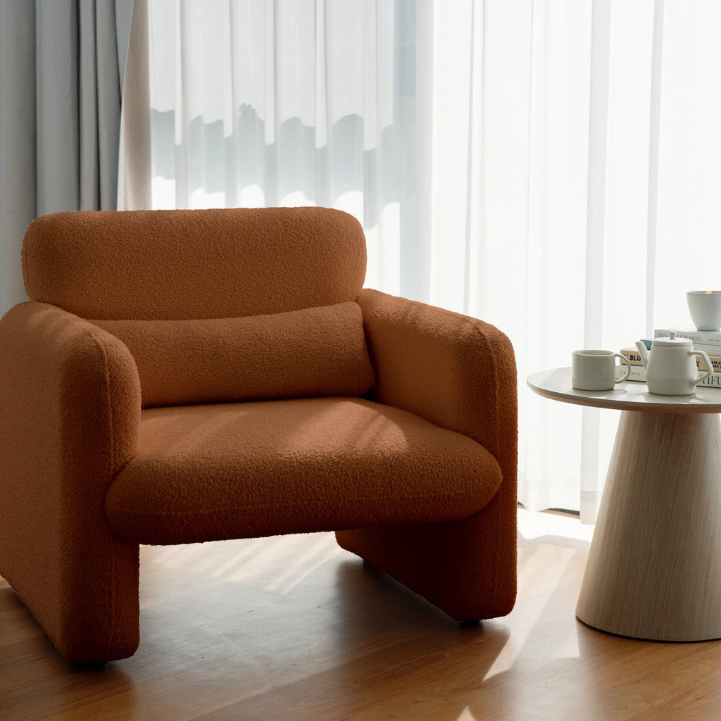 An image featuring an amber-coloured armchair with a minimalist design