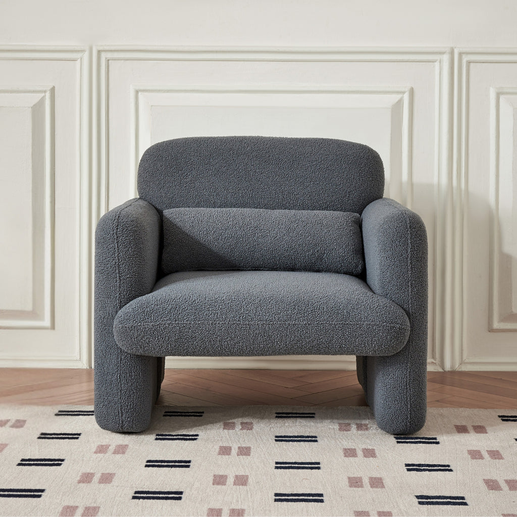 A grey upholstered Astrid Armchair with a minimalist design,showing its profile with a focus on its shape and colour