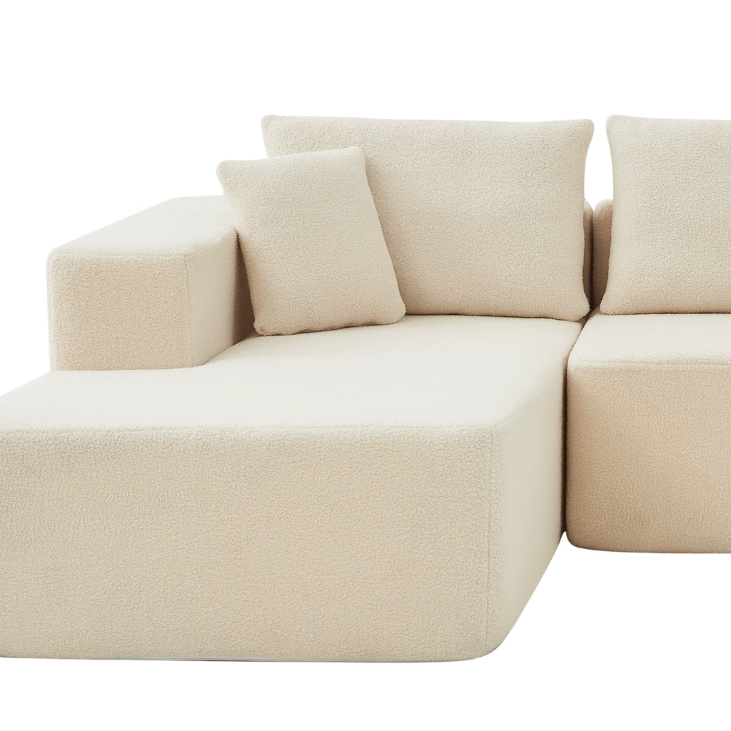 A close-up cream modular sofa with a left-arm chaise and right-arm seat, upholstered in synthetic lambswool, with a low-profile design.