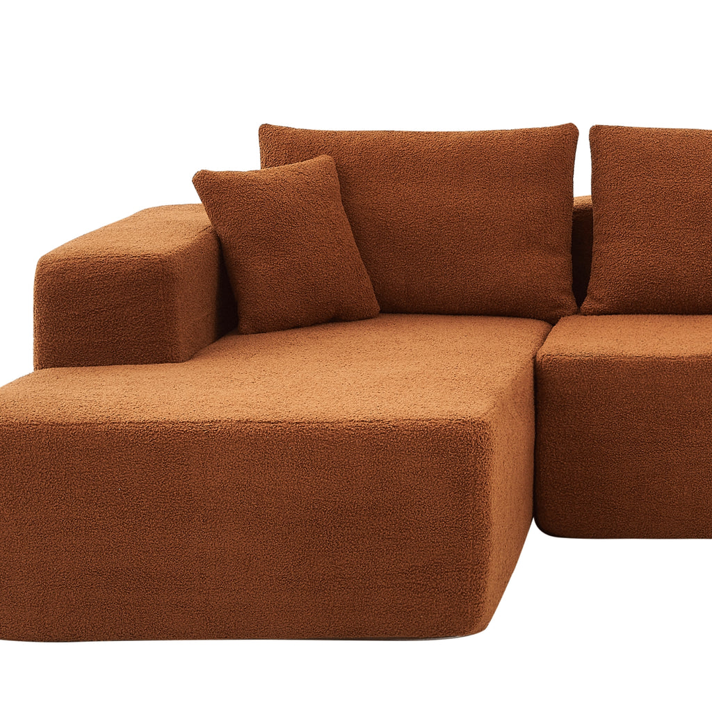 A close-up terracotta orange modular sofa with a left-arm chaise and right-arm seat, upholstered in synthetic lambswool, with a low-profile design.