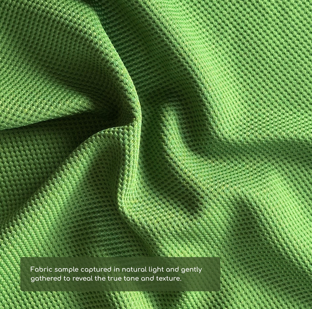 Close-up of green fabric with a subtle texture, captured in natural light.