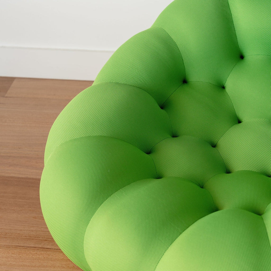 Photos green buttoned sofa on a wooden floor with a white wall background