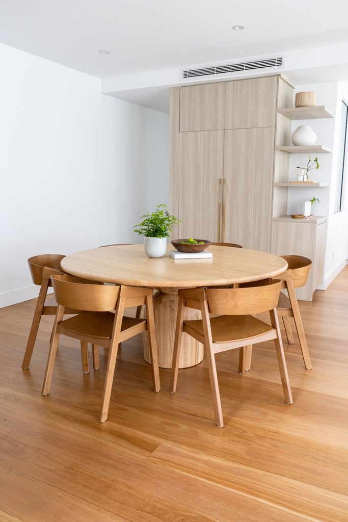 A round wooden dining table iwith chairs in a dining area