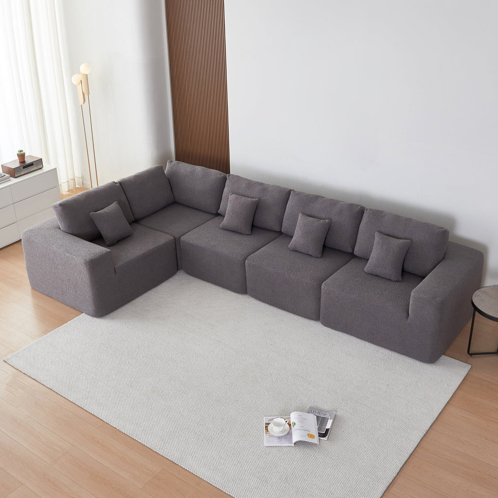 Grey sectional sofa in a modern living room with a rug and a small table.