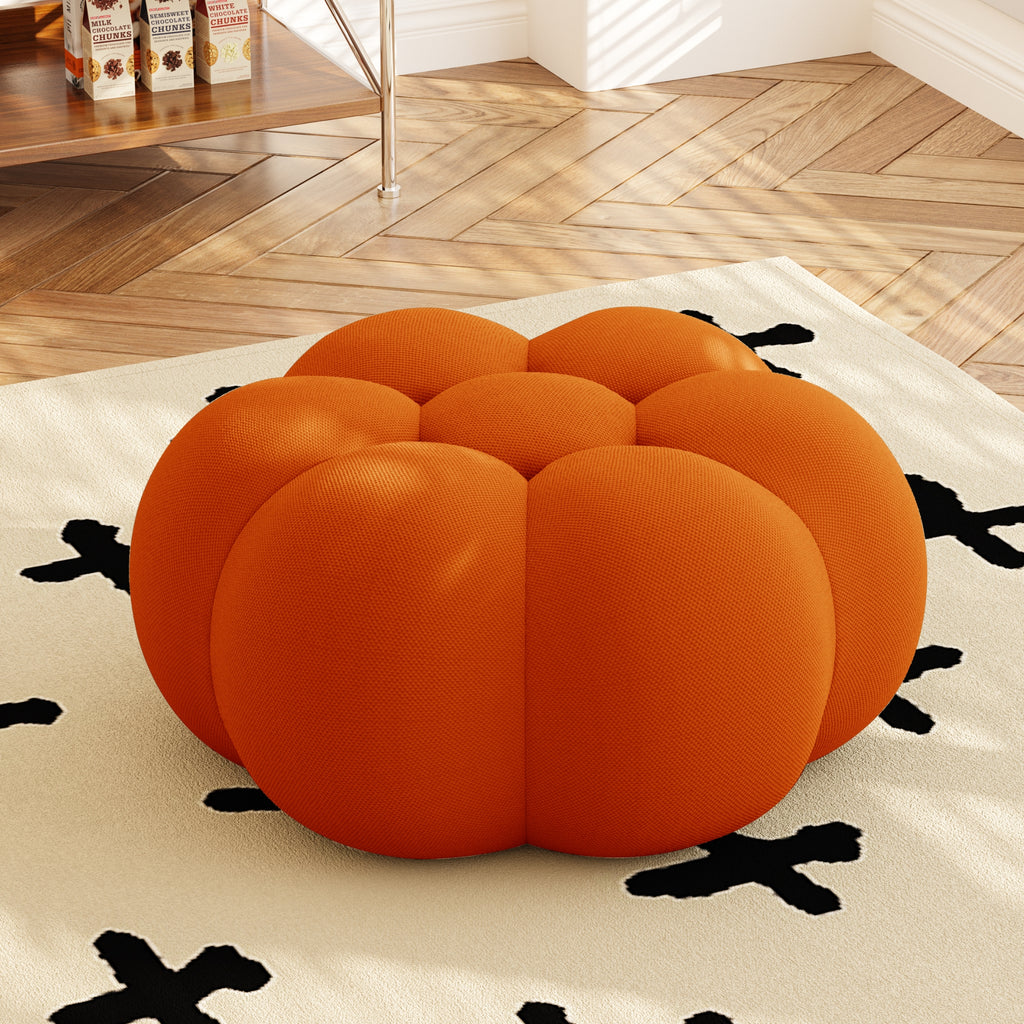 Orange pumpkin-shaped ottoman on a rug with a wooden floor background