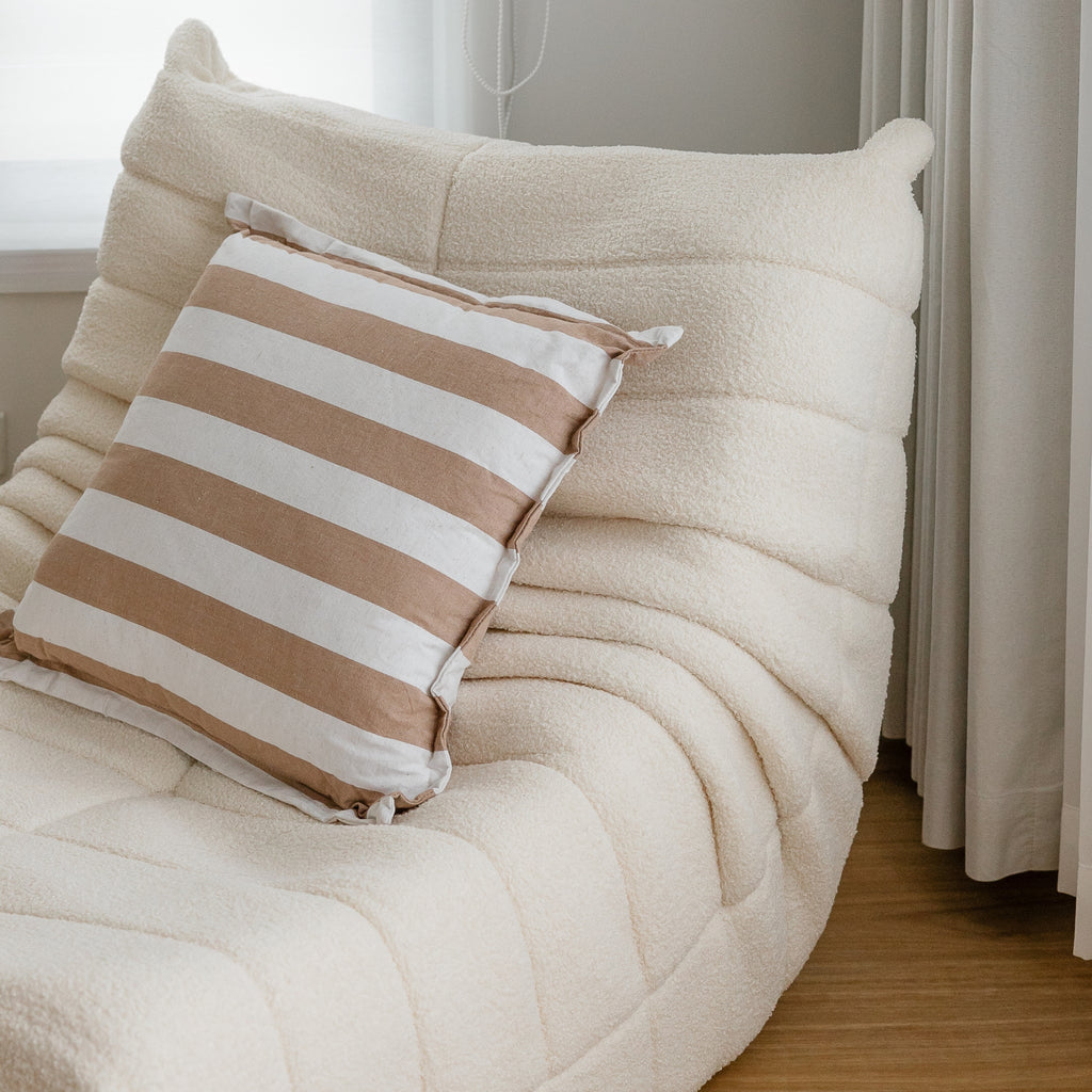 A  single cream  sofa featuring a curved silhouette and synthetic lambswool upholstery.
