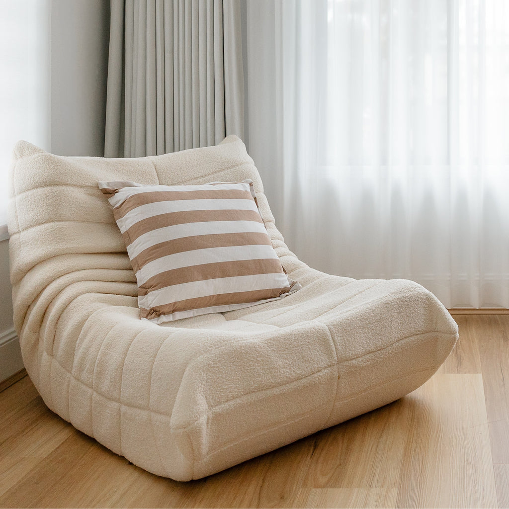 An image featuring a cream-coloured, single sofa with a cushion