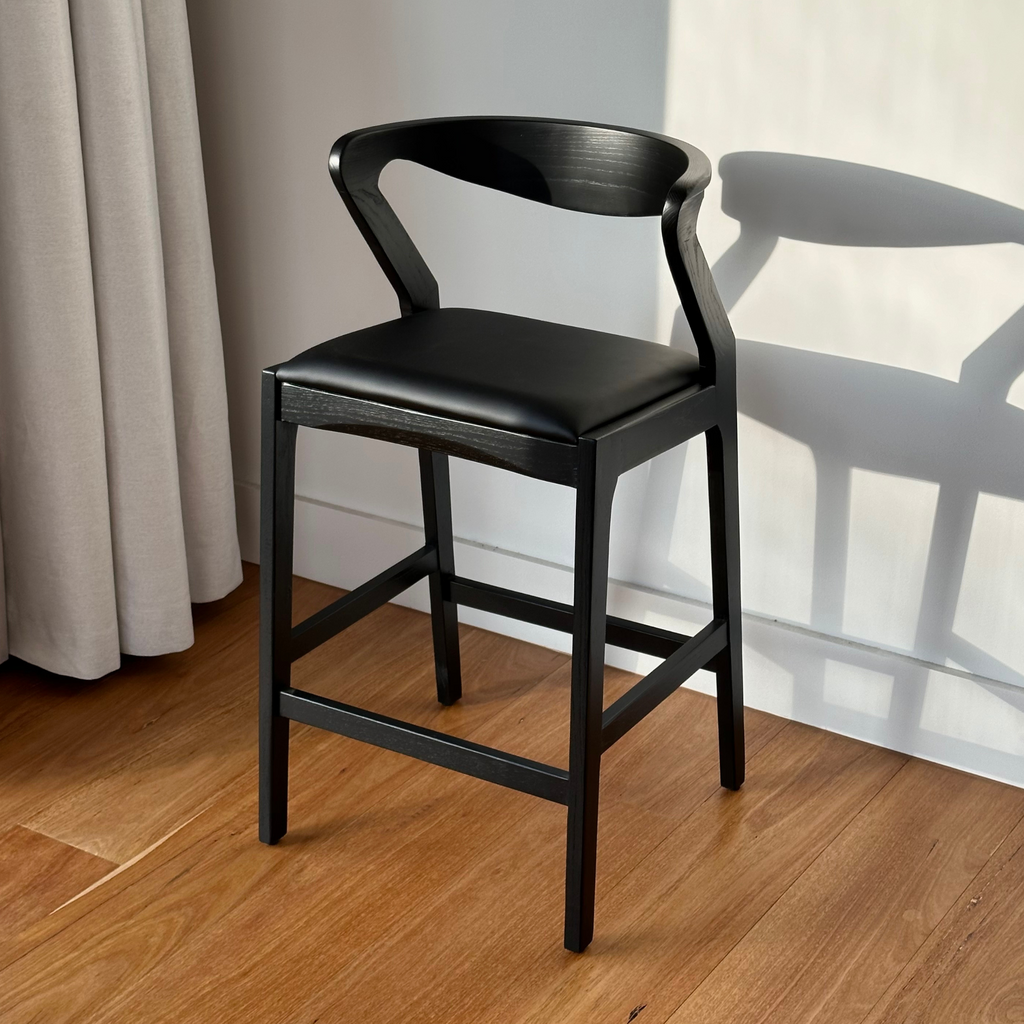 Black bar stool with a modern design on a wooden floor